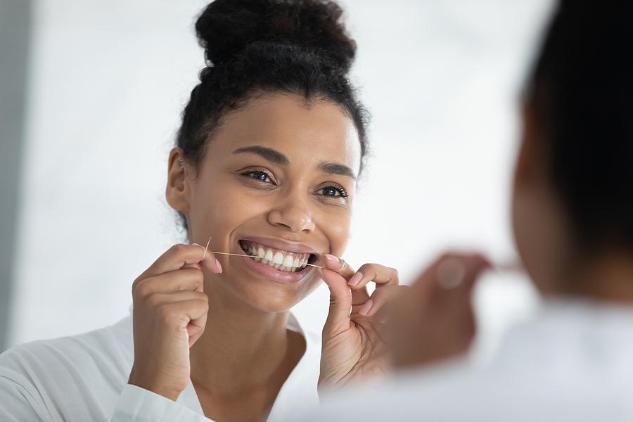Beautiful smiling african woman holding dental floss cleaning teeth